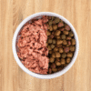 A dog bowl with raw food on one side and kibble on the other