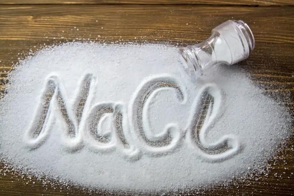 a salt shaker and NaCL written on a pile of salt