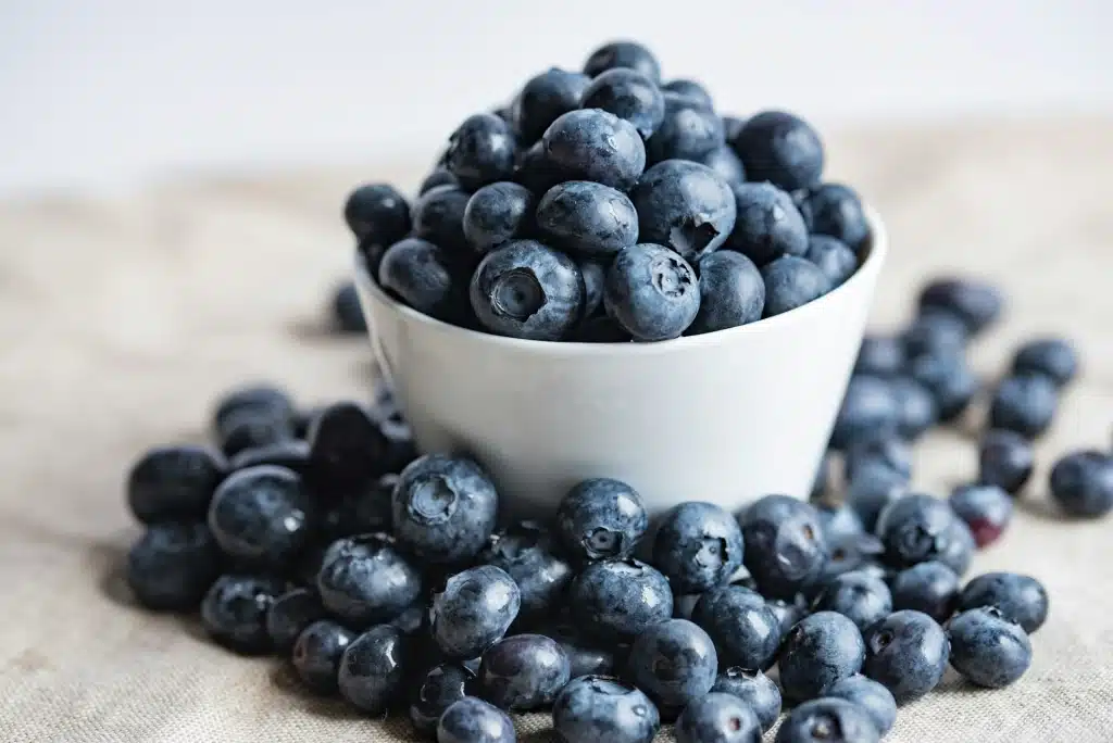 blueberries in a white bowl on a table.